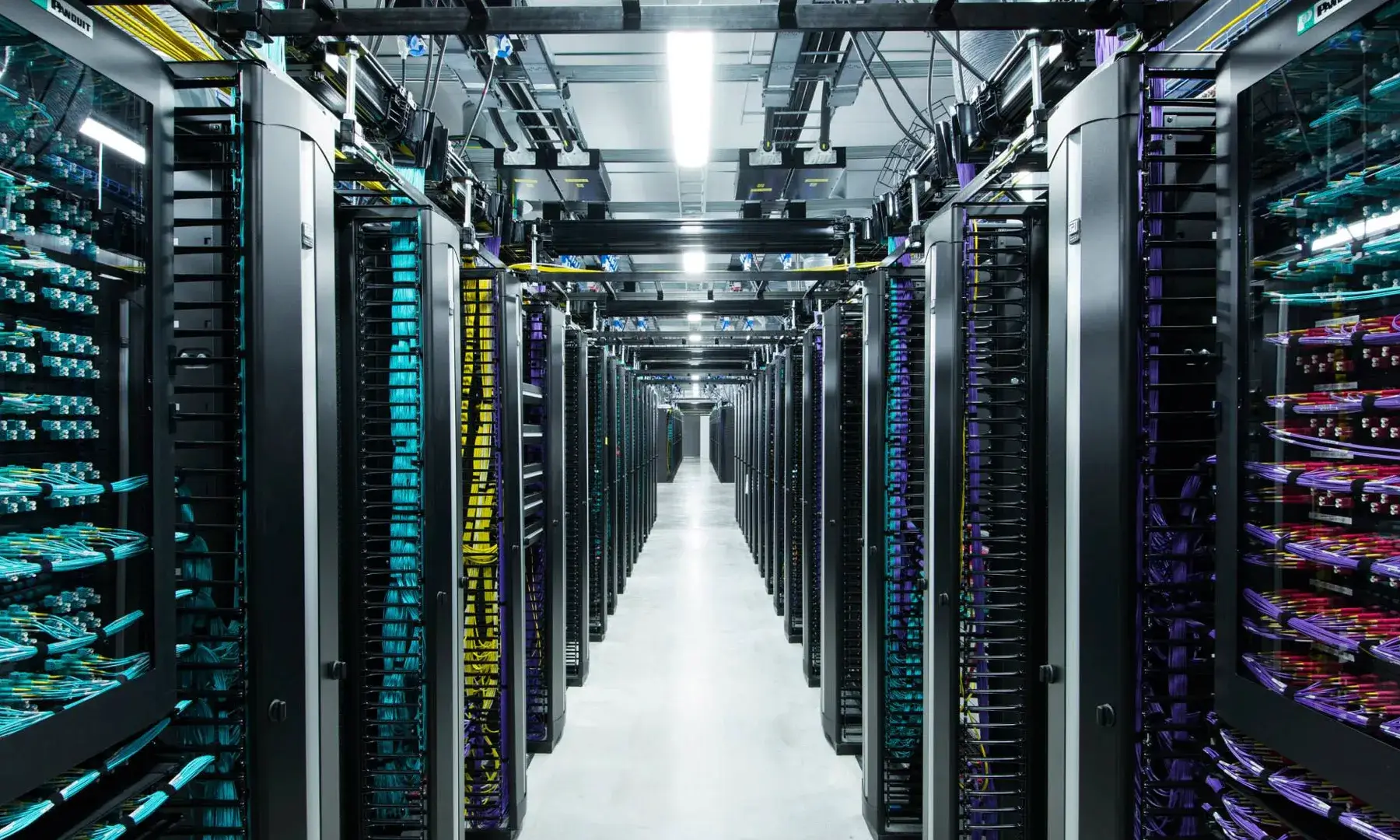 A modern network operations center with servers and data visualisations.